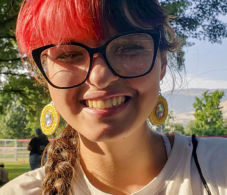 Girl with red hair and glasses smiling.