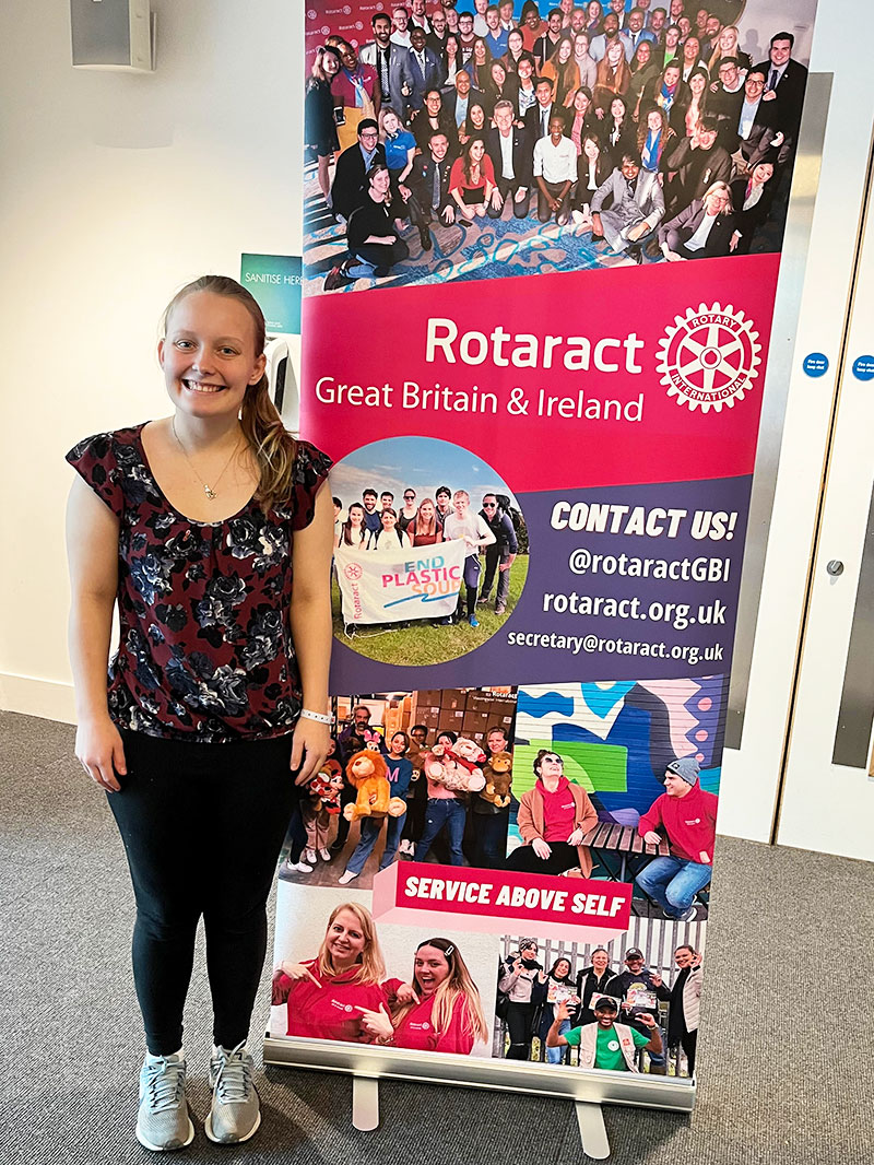 Girl standing in front a Rotaract sign. 